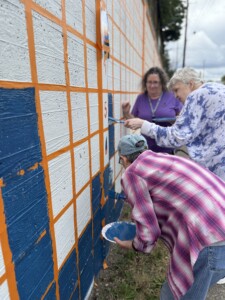 Visitors painting a wall for Mural for Memories event at The Village Senior Living in Tacoma, WA