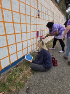 Visitors painting a wall for Mural for Memories event at The Village Senior Living in Tacoma, WA