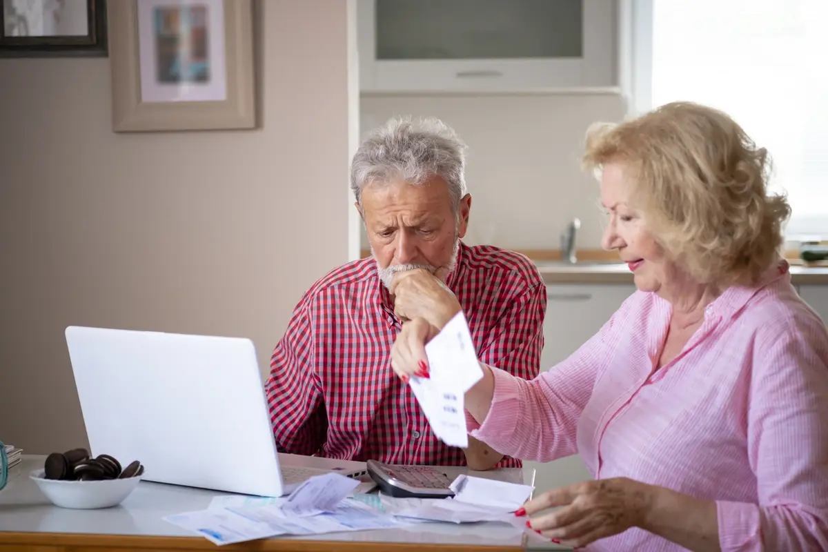 Serious older couple reviewing finances at home and asking when is assisted living needed for their future