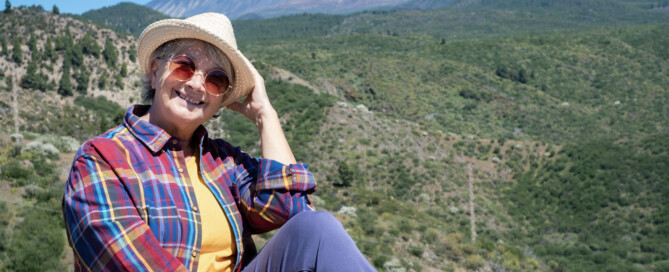 Older woman using summer safety tips for seniors of hat, sunglasses, and long sleeve shirt